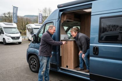 Couple souriant examine un van aménagé à la concession